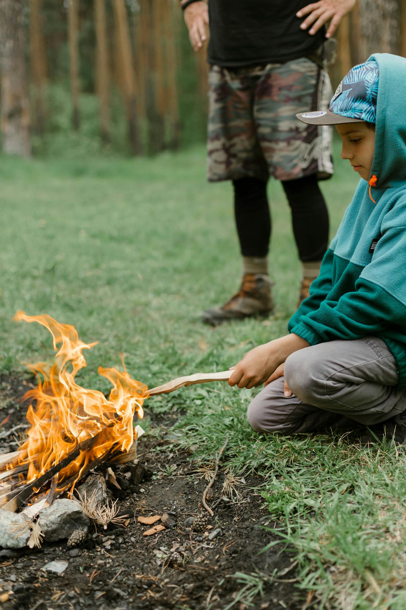 A Boy in Green Hoodie Burning a Stick on Bonfire